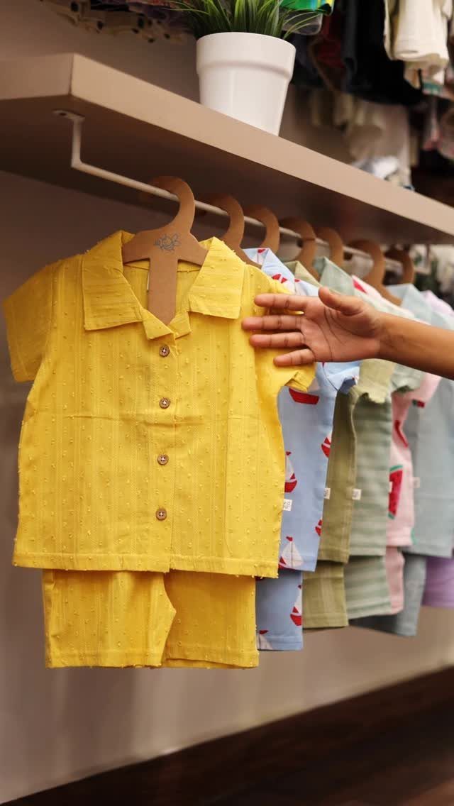Yellow infant shirt and shorts set hanging on a rack with other clothes.