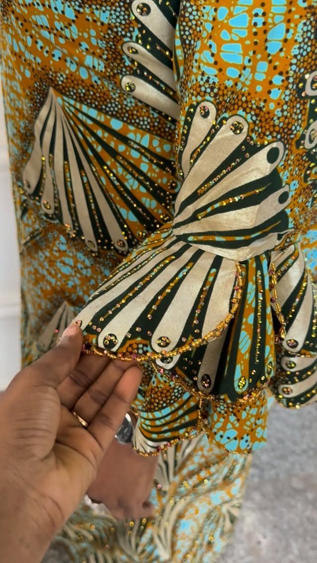 Vibrant orange and blue Ankara fabric garment with beaded fan-shaped sleeve details.
