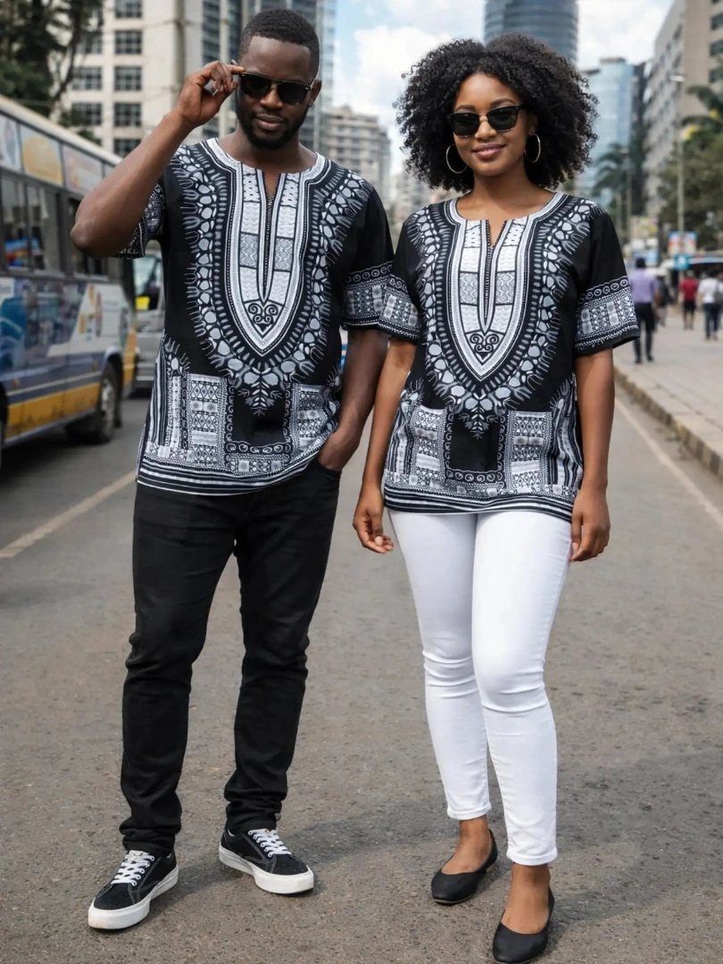 Man and woman wearing matching black and white dashiki shirts on a city street.