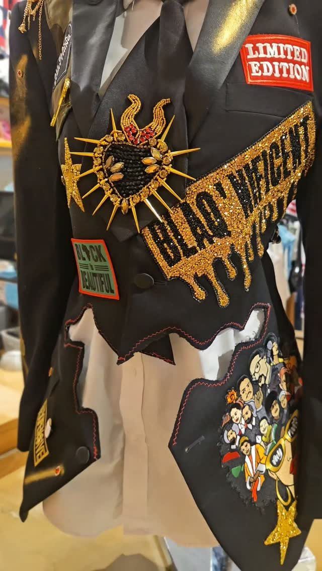 Black blazer with gold sequins, 'Black Magnificent' text, and cultural patches over white shirt