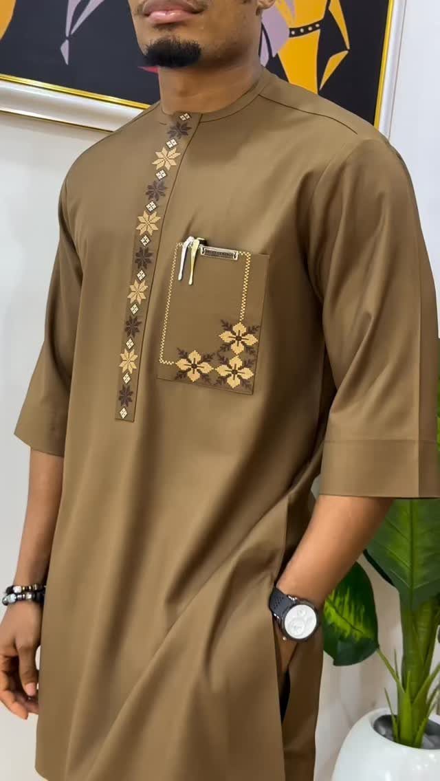 Man wearing a brown embroidered tunic with gold floral patterns on the chest.