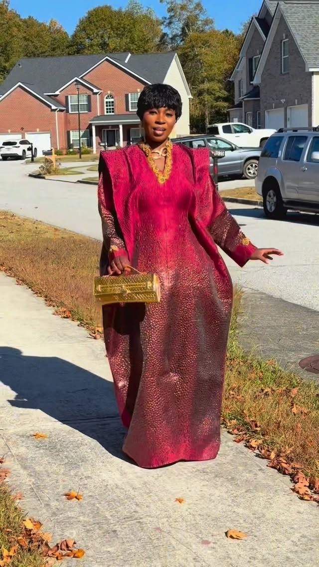 Woman wearing a shimmering magenta and gold traditional African gown on a sidewalk