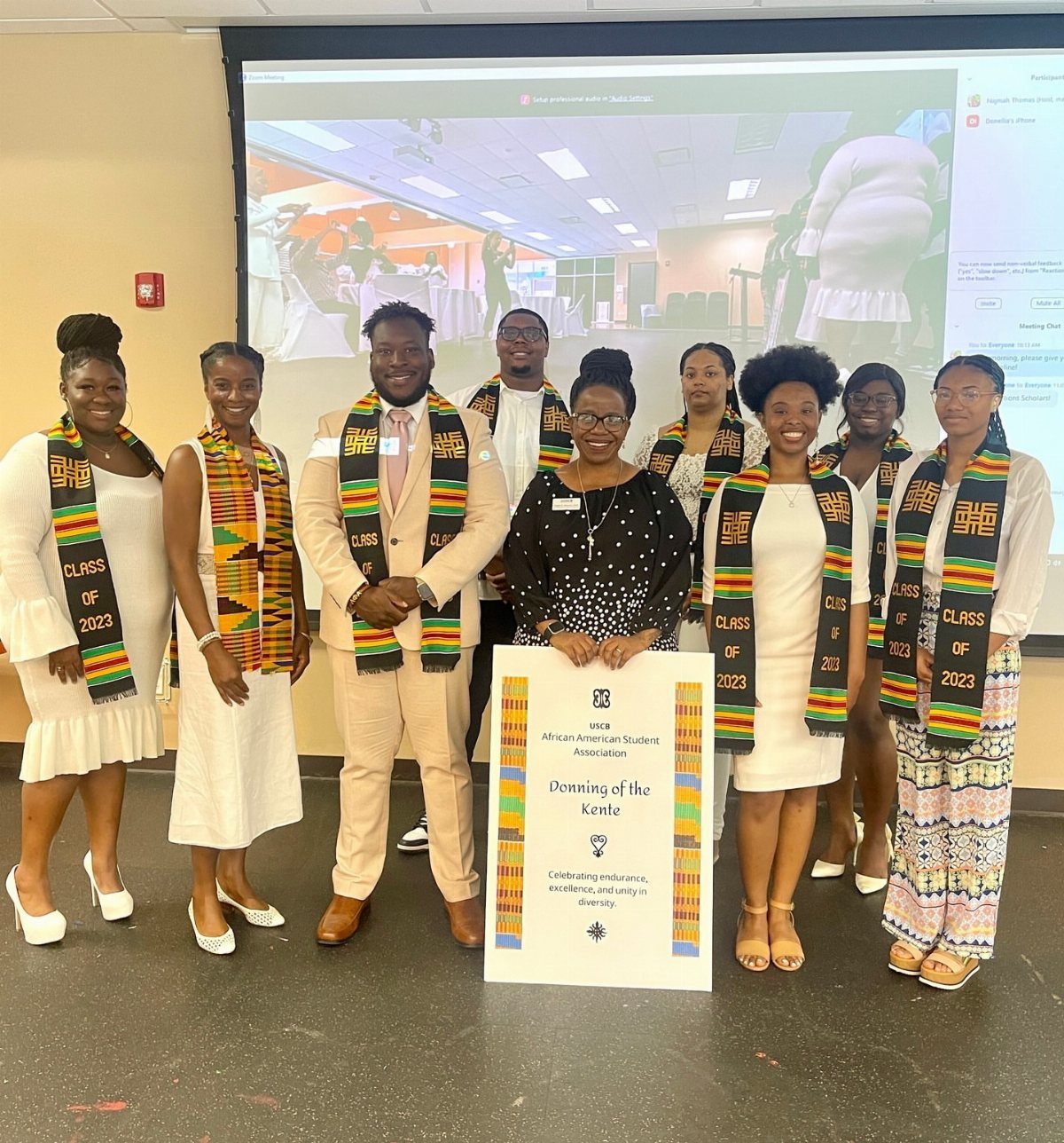 Group of African American graduates wearing white outfits and traditional Kente cloth stoles.