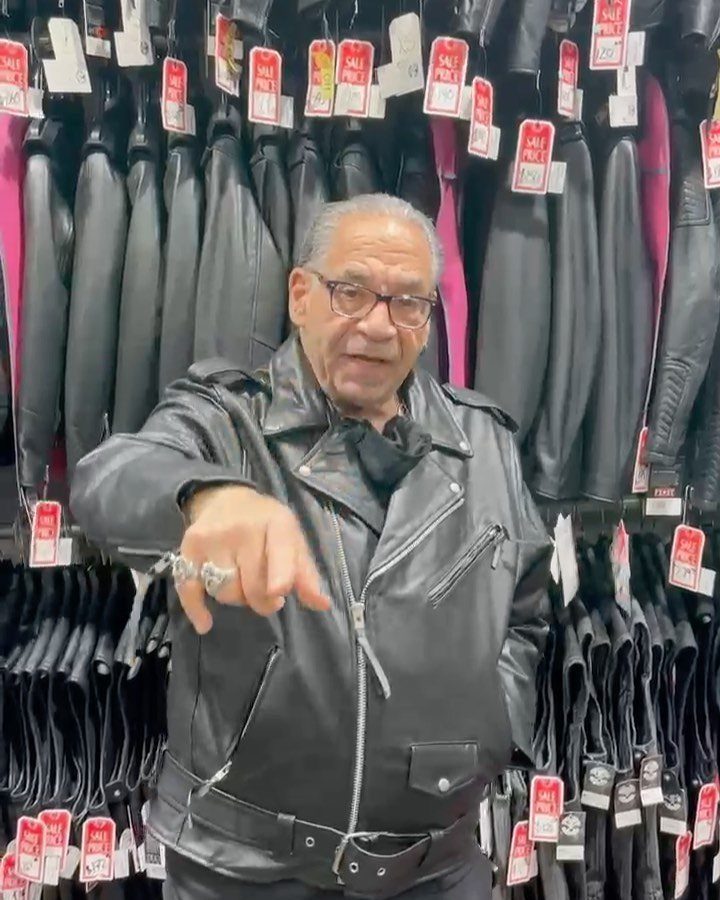 American Culture Clothing: 6 Ideas From Denim to Biker Jackets 6 Man in black leather motorcycle jacket pointing forward in a clothing store.