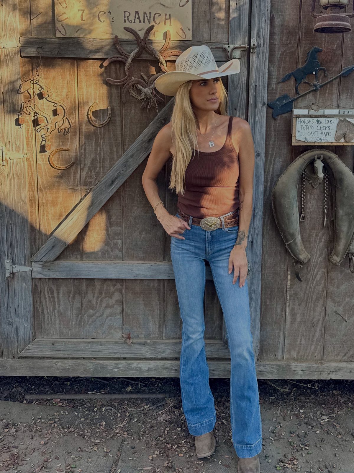 American Culture Clothing: 6 Ideas From Denim to Biker Jackets 1 Woman in cowboy hat and flared blue denim jeans posing by wooden barn.