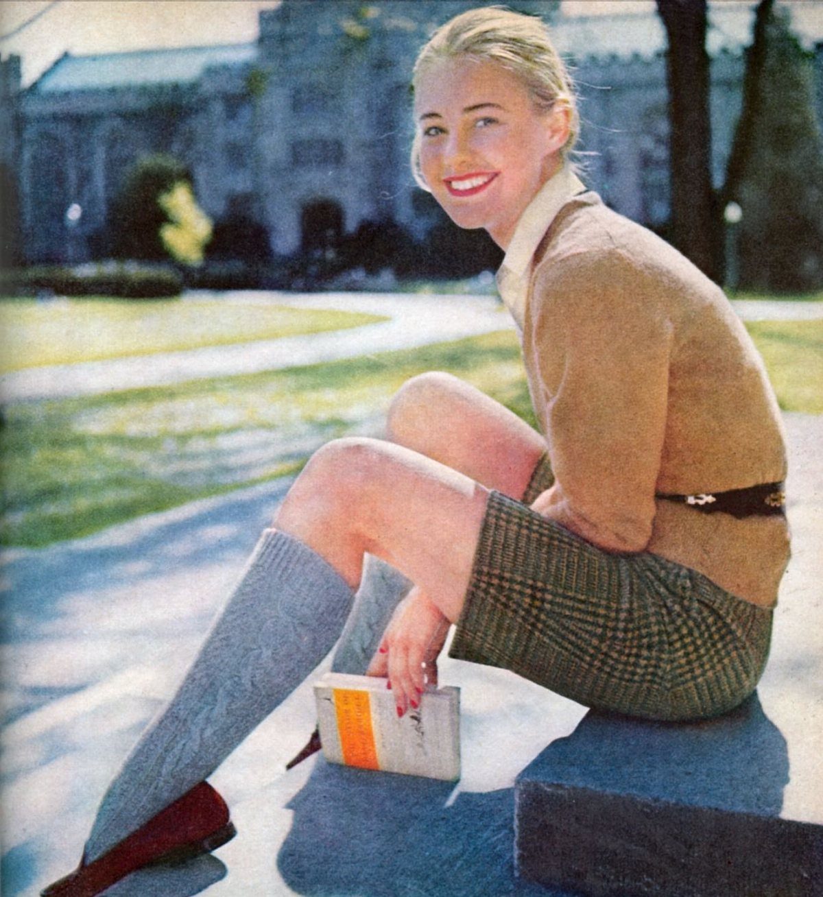 American Culture Clothing: 6 Ideas From Denim to Biker Jackets 2 Woman in preppy attire with a cardigan and plaid skirt sitting on campus.