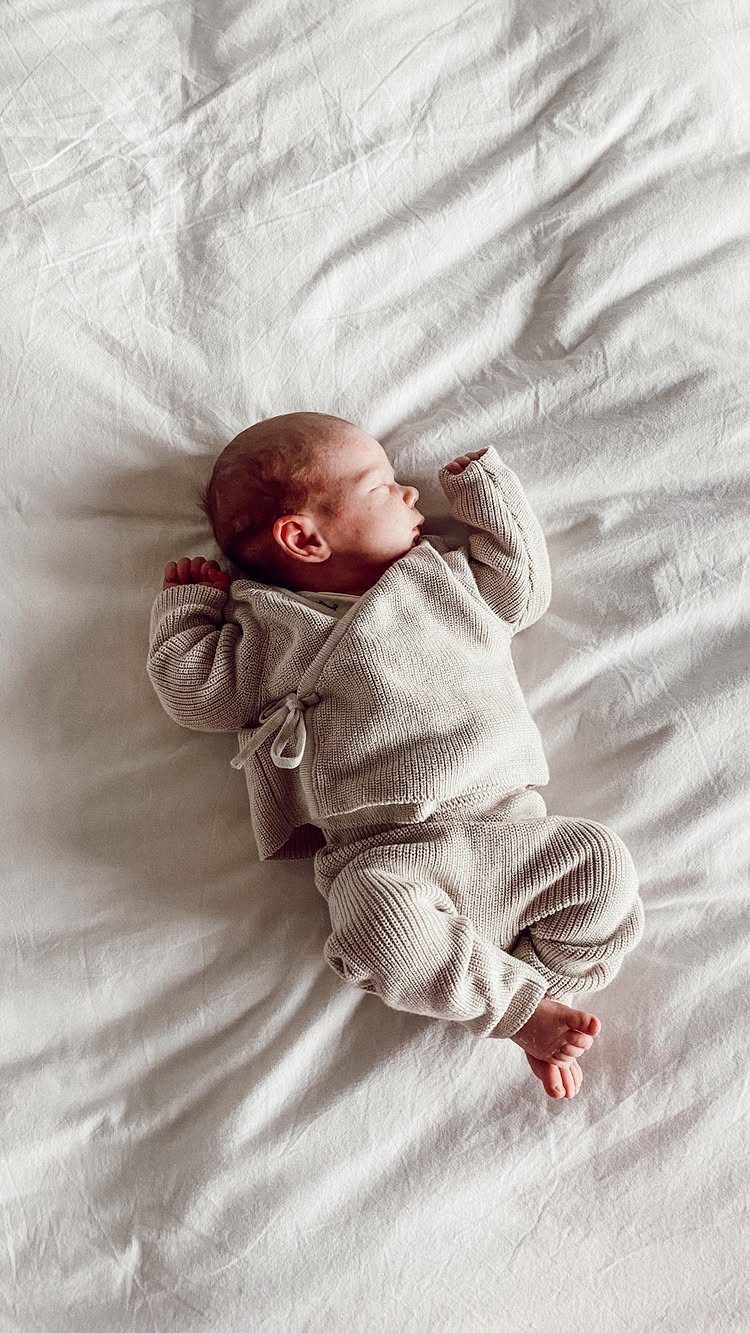 Newborn baby wearing a beige textured knit wrap top and matching pants.