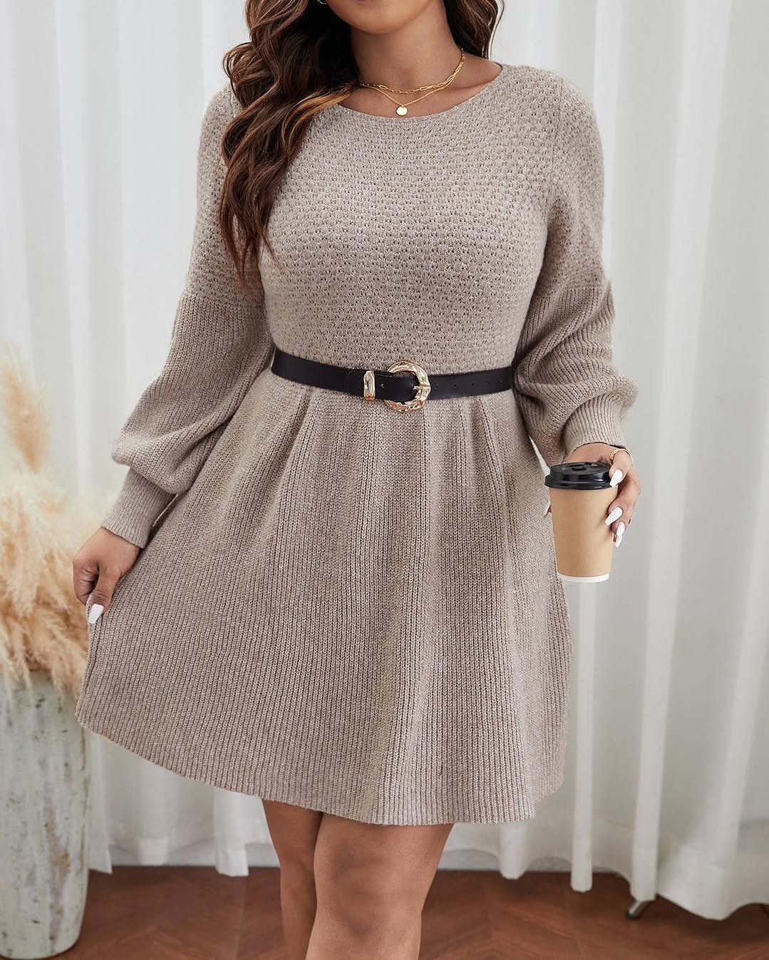 Plus-size woman in a beige knit dress with a black belt holding coffee.