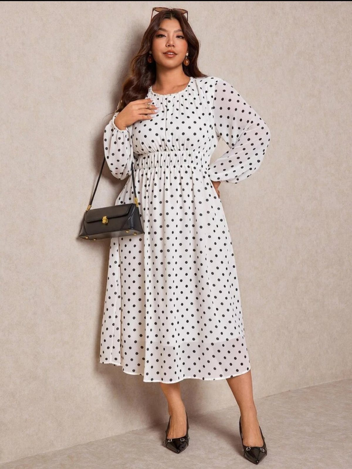 Plus-size woman wearing a white polka dot midi dress and black heels.