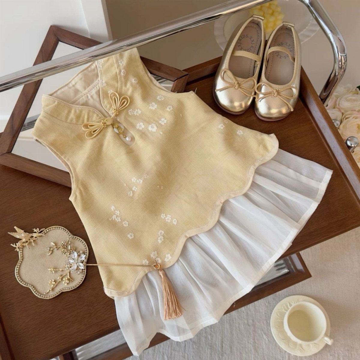 Chinese Infant Clothing: 7 Ideas for Baby Outfits 5 Yellow embroidered qipao top and white pleated skirt with gold shoes on table