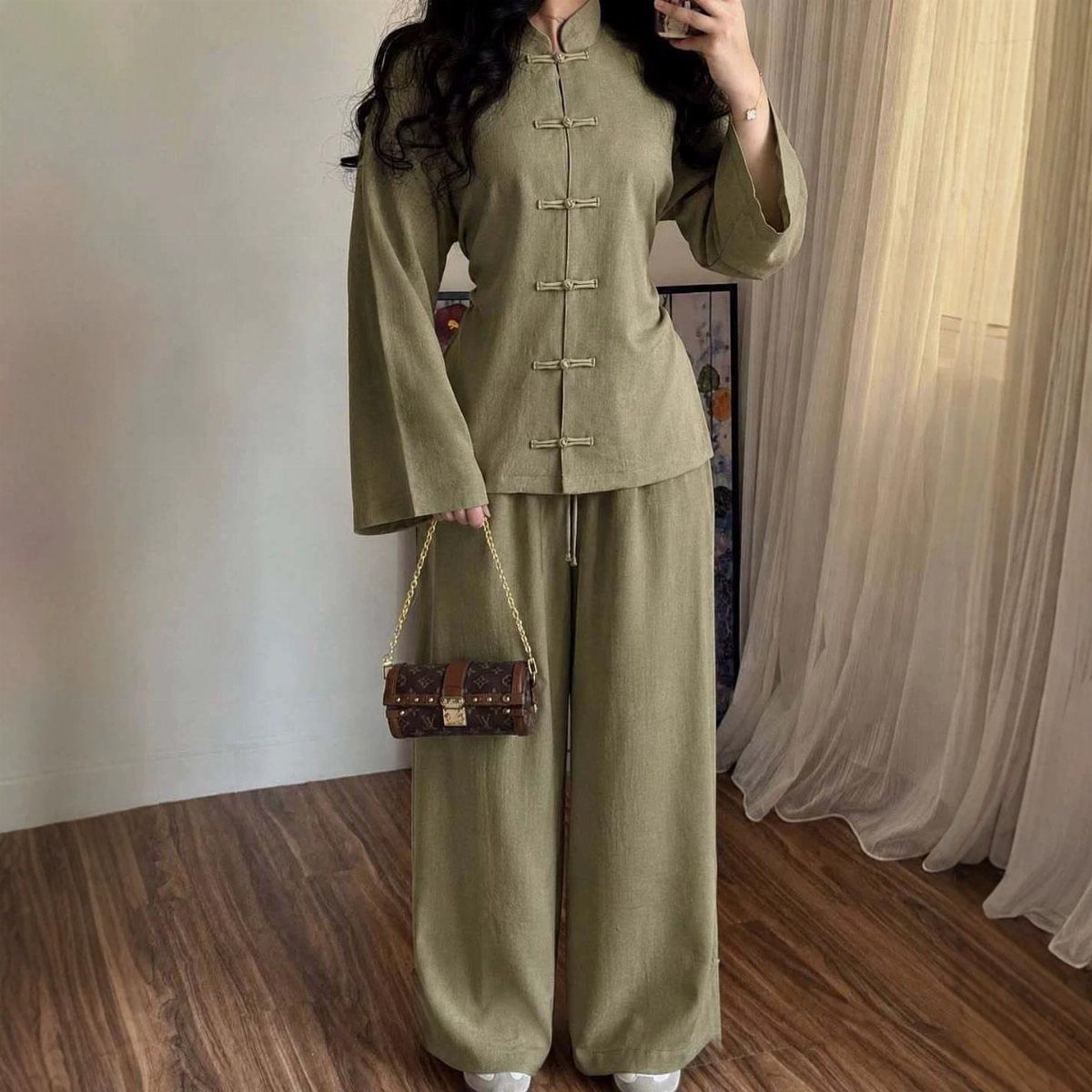 Person wearing olive green Chinese inspired matching set with frog button top and trousers.