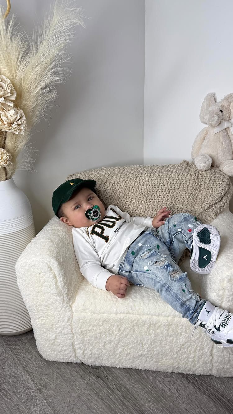 Edgy Infant Clothing Ideas: 6 Looks from Skater to Goth 6 Infant in a green cap and distressed jeans reclining in a fuzzy white chair.
