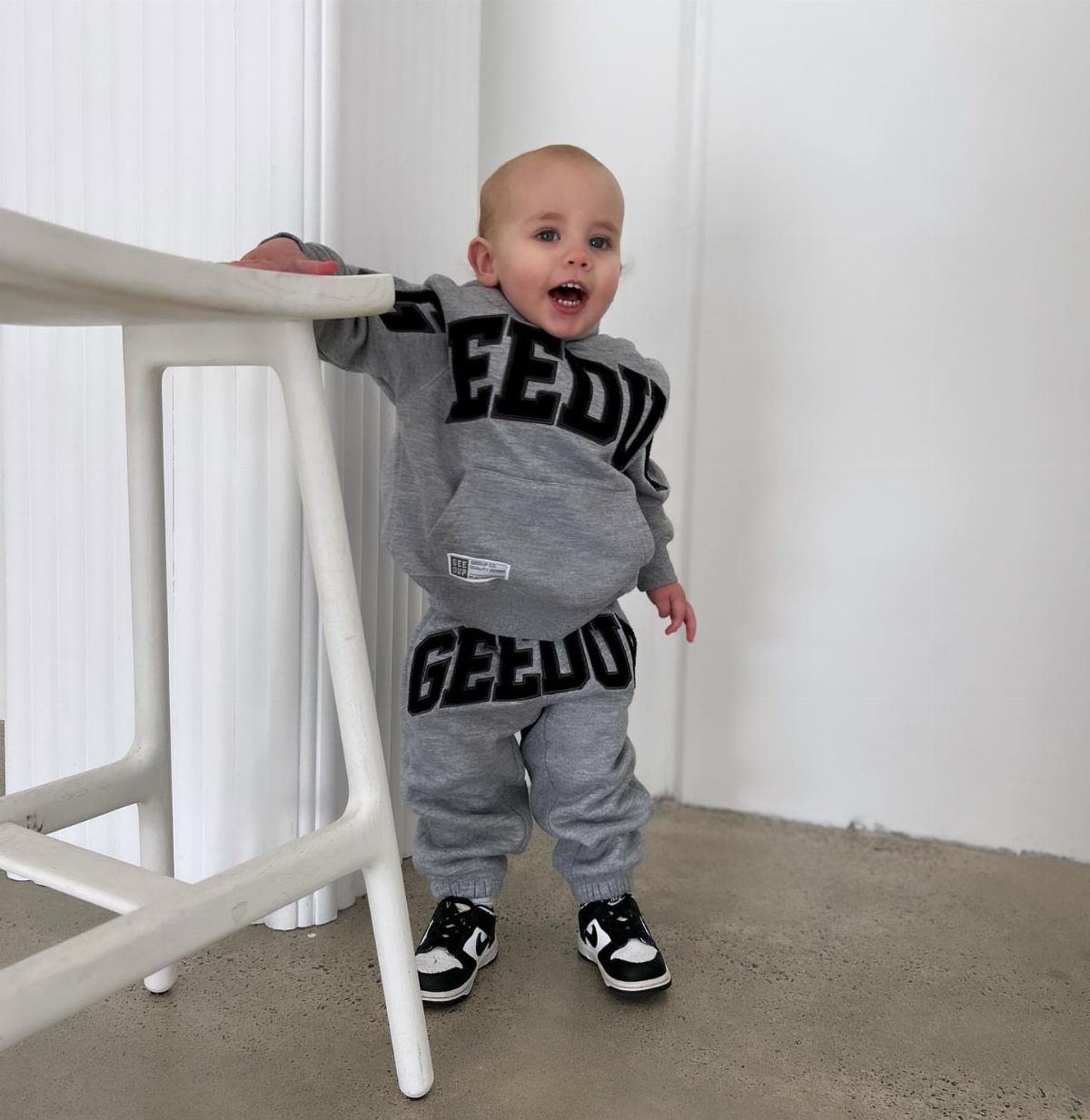 Edgy Infant Clothing Ideas: 6 Looks from Skater to Goth 1 Baby in grey streetwear hoodie and joggers with black and white sneakers.