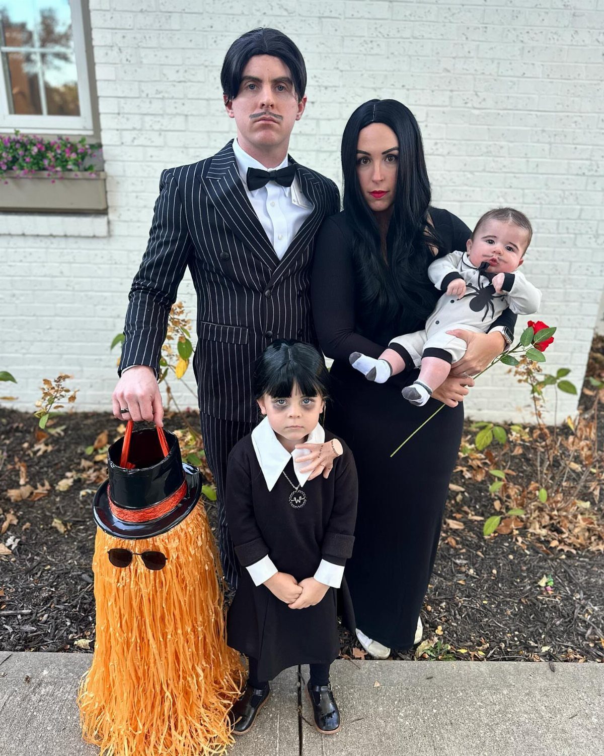 Family dressed as the Addams Family including a baby and a young girl.
