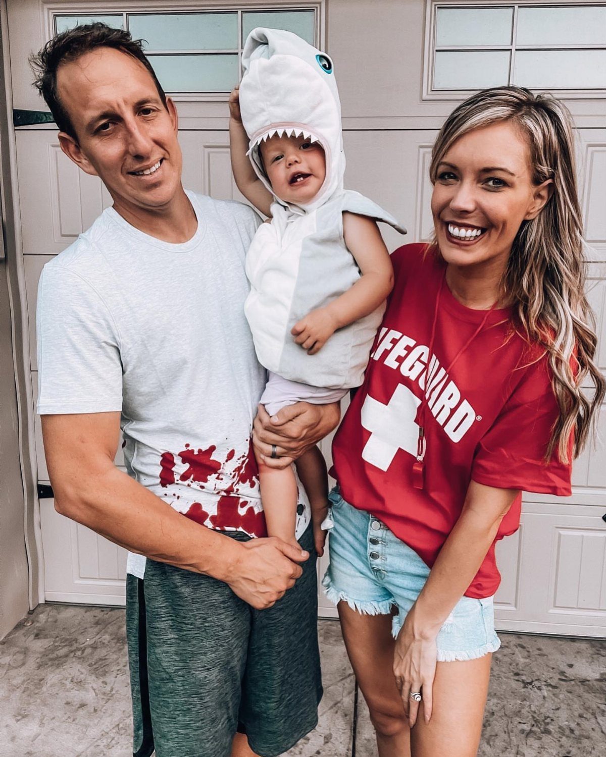 Family posing in costumes with a baby wearing a white shark outfit.