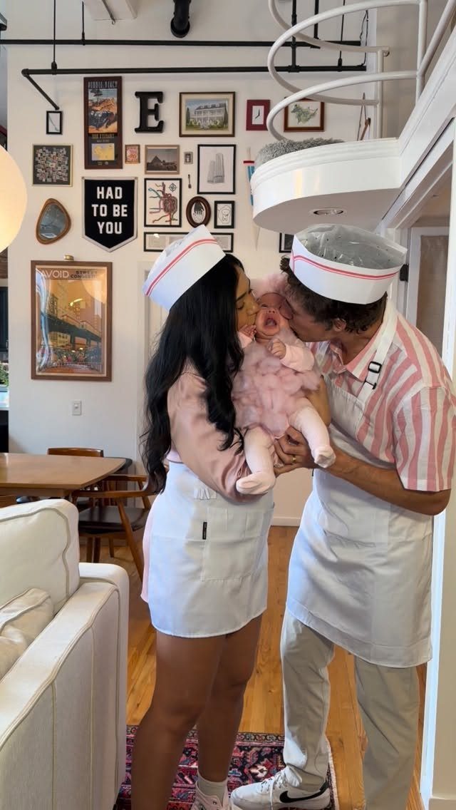 Parents dressed as chefs holding a baby dressed as a pink cupcake.