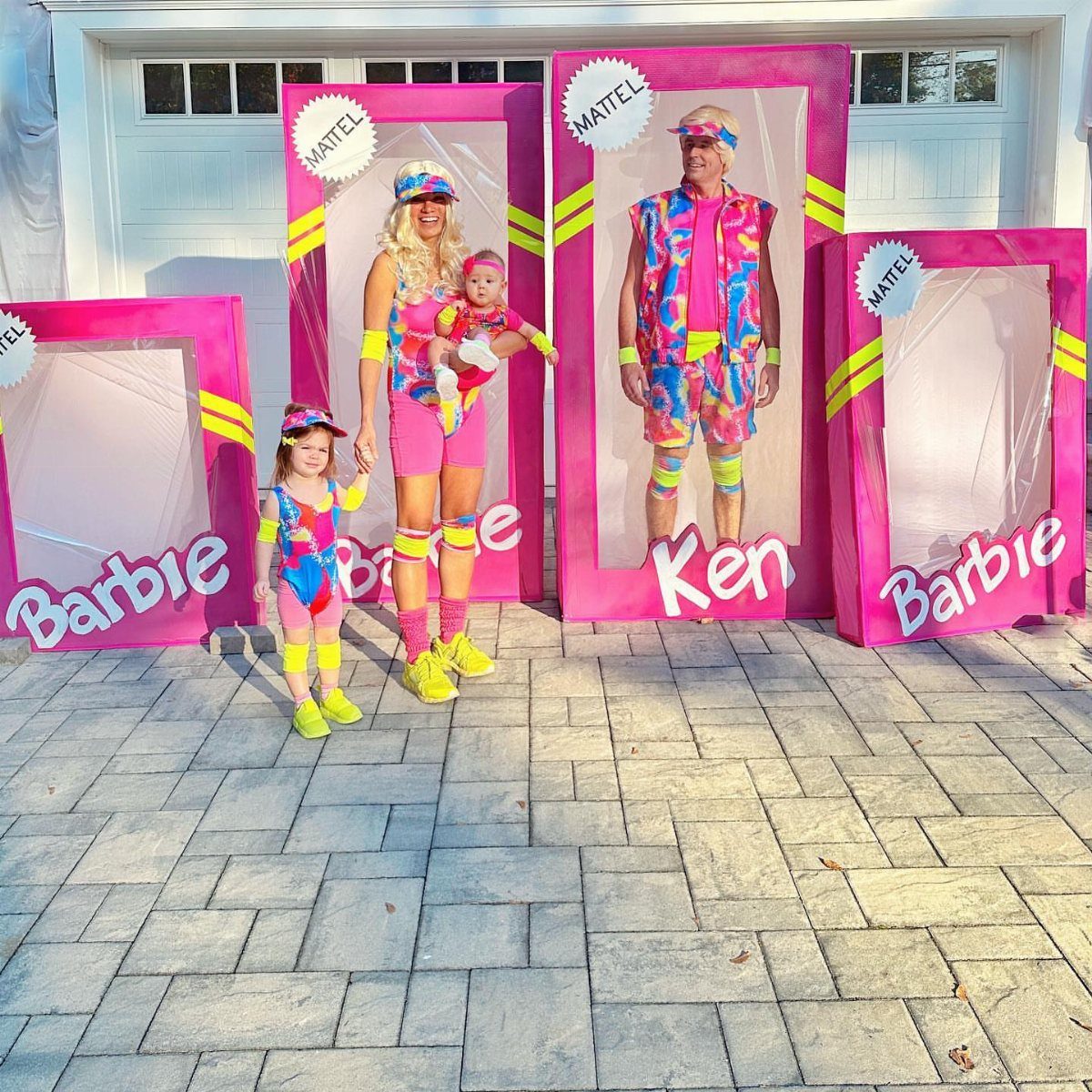 Family in neon workout gear posing inside pink Barbie and Ken toy boxes.