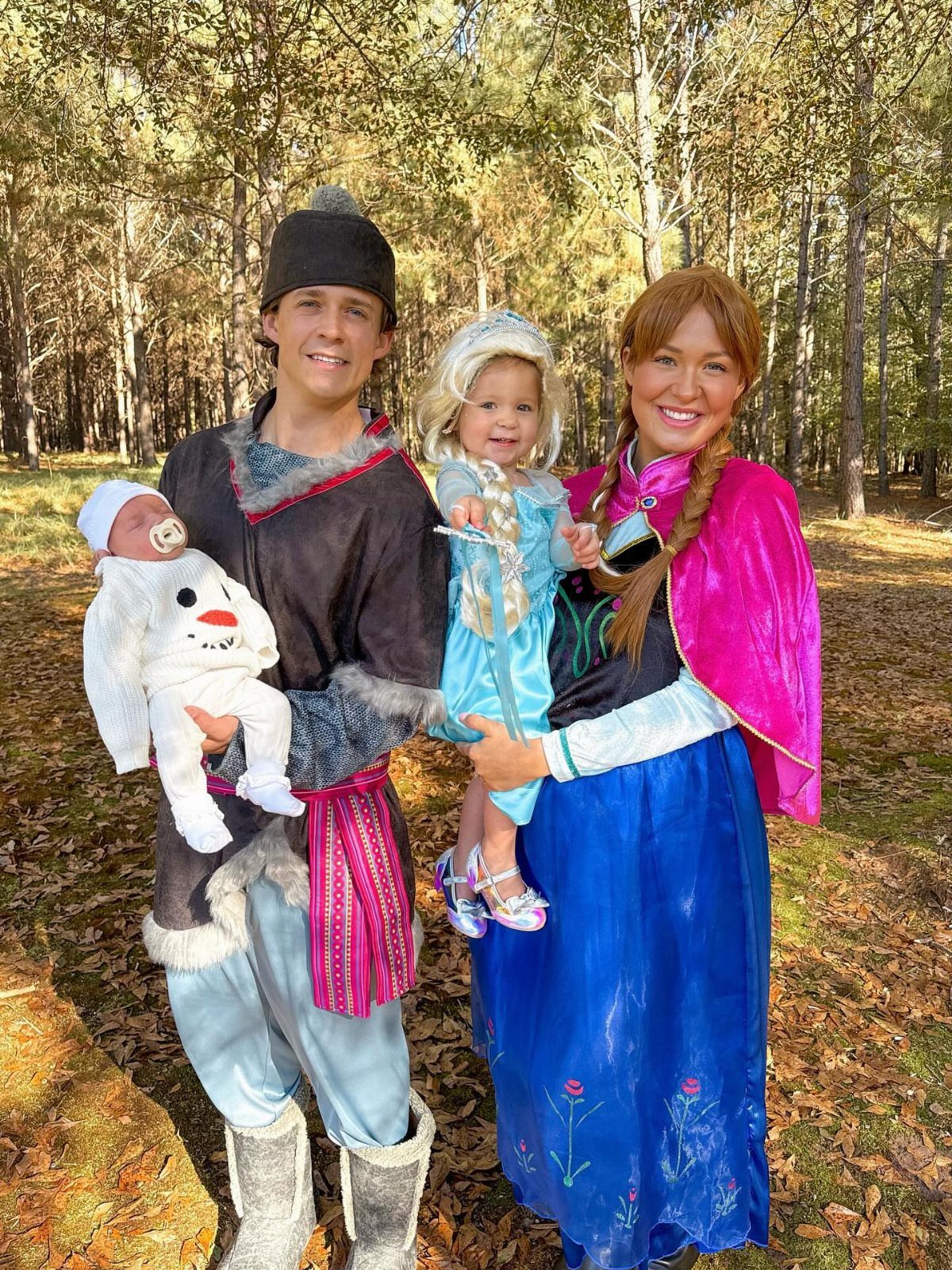 Family in Frozen costumes including a newborn baby dressed as Olaf in woods