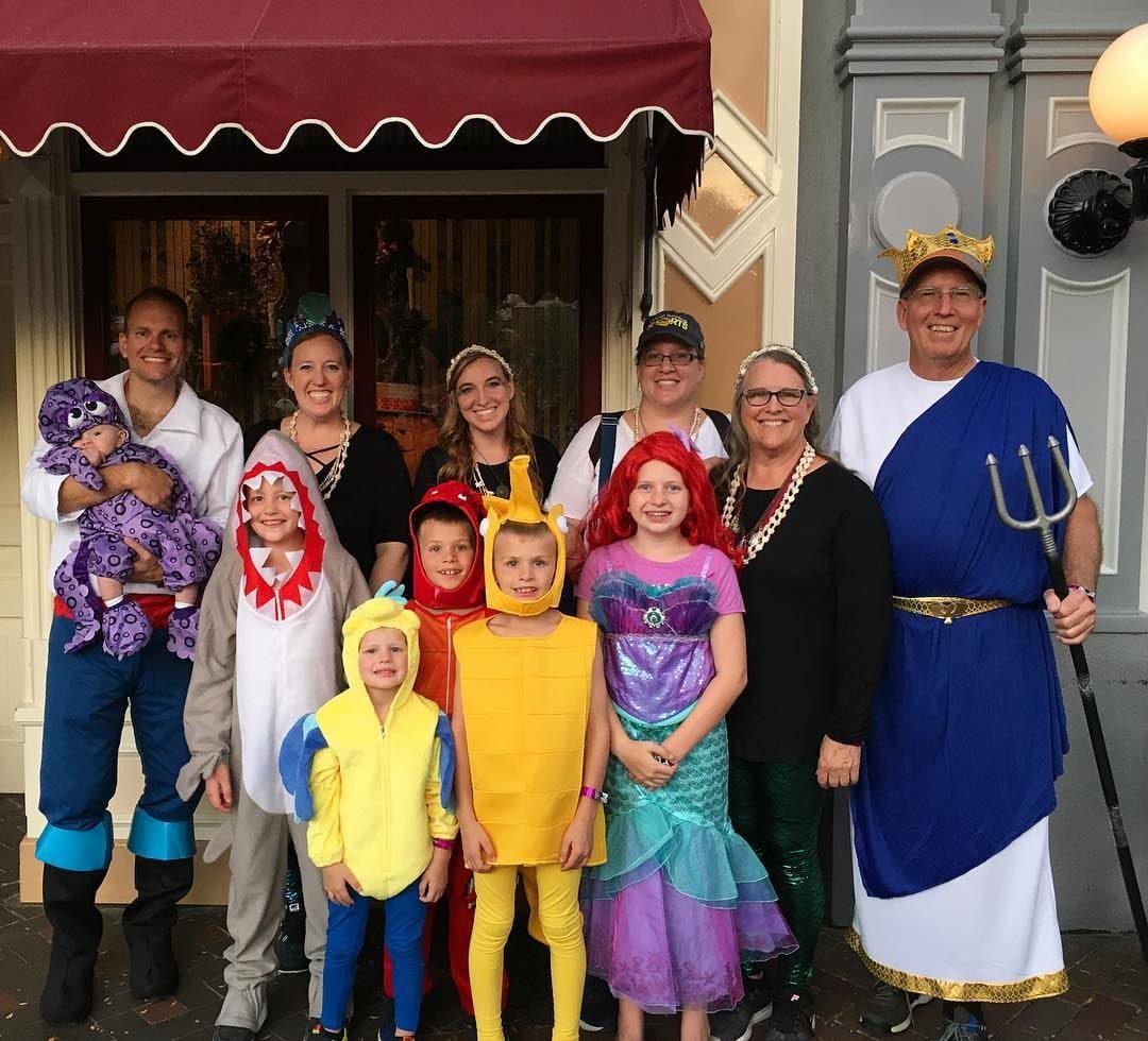 Family in Little Mermaid costumes including a baby fish and King Triton.