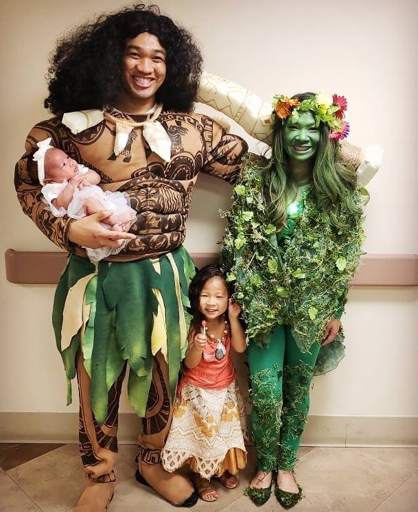 Family in Moana costumes including a man holding a newborn baby girl.