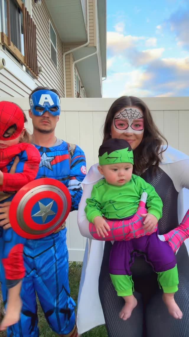 Family in superhero costumes including Captain America, Spider-Gwen, Spider-Man, and a baby Hulk.