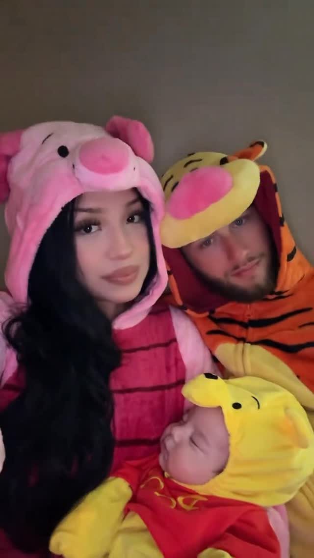 Family wearing Winnie the Pooh character costumes including a newborn baby as Pooh.