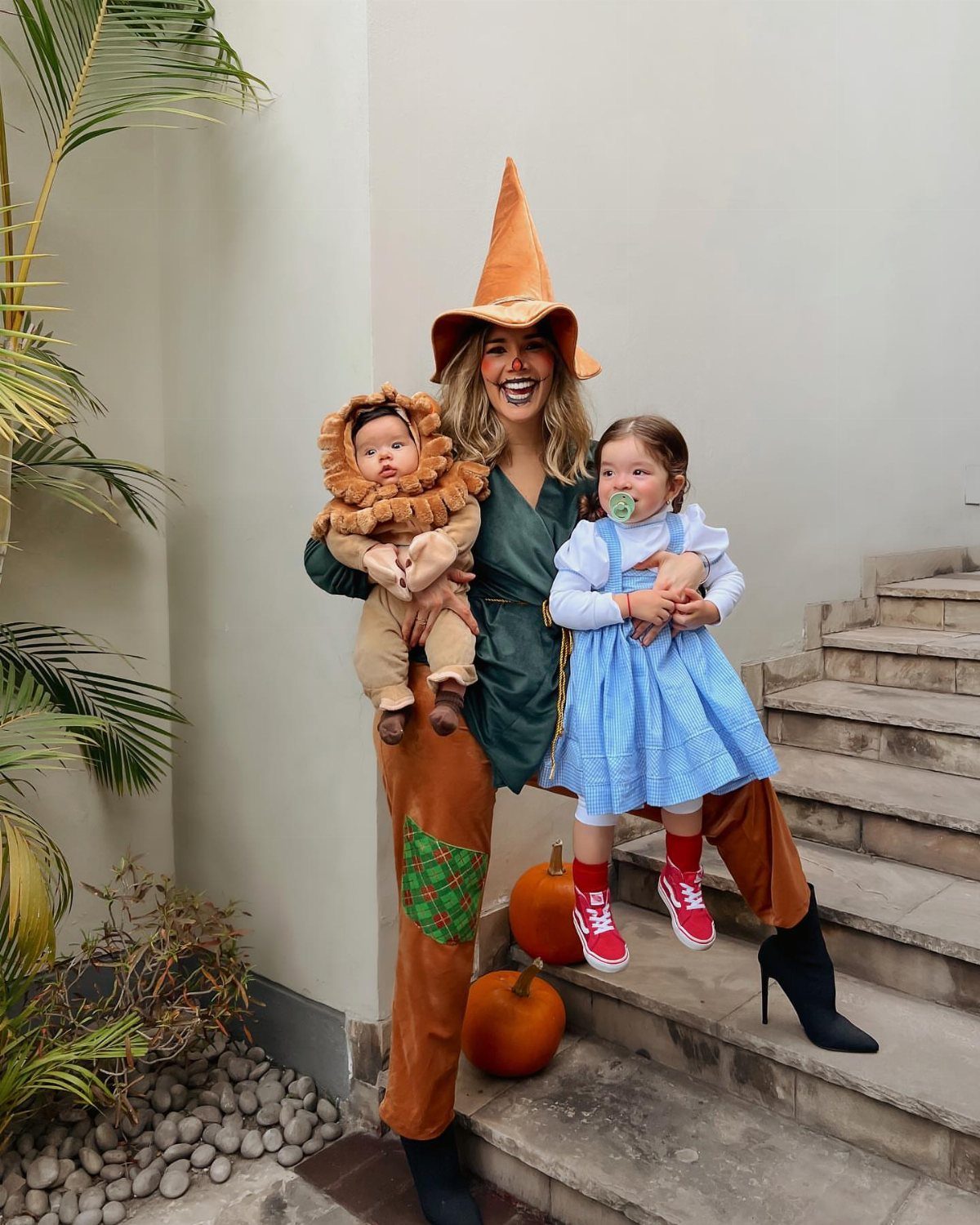 Woman, baby lion, and girl in blue gingham dress posing as Wizard of Oz characters.