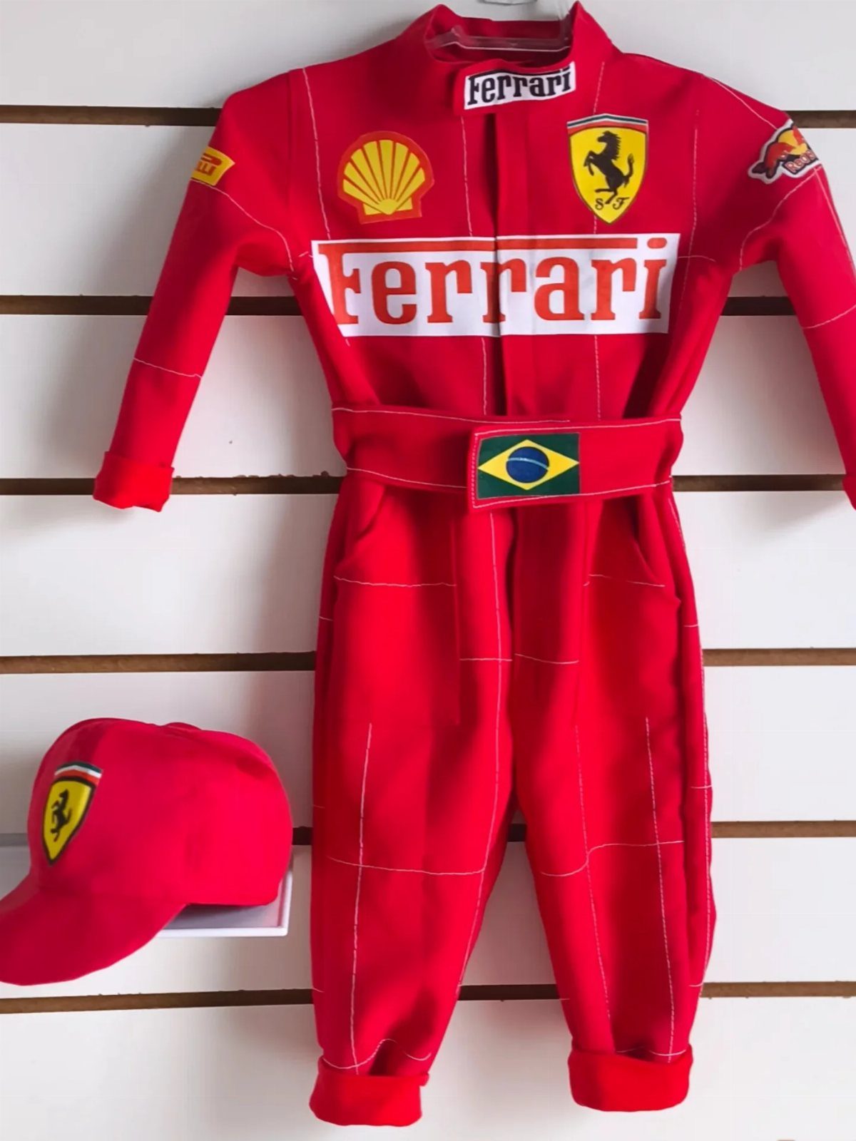 Ferrari Newborn Clothes: 8 Ideas for Red Racing Looks 6 Red Ferrari baby jumpsuit and matching cap displayed on a white slatted wall.