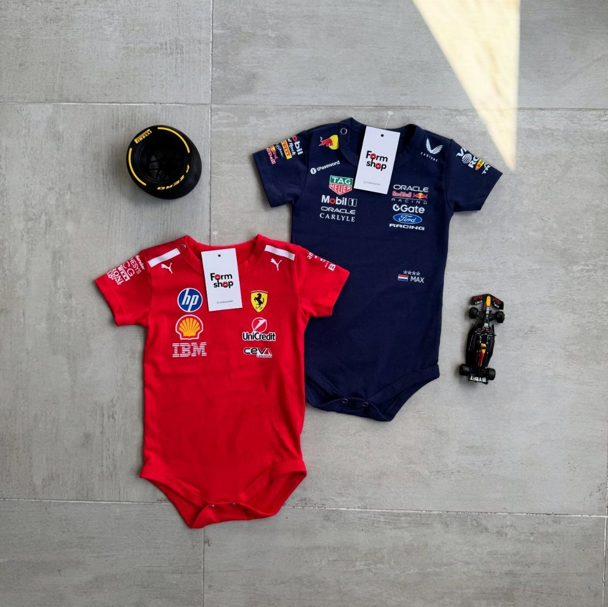 Ferrari Newborn Clothes: 8 Ideas for Red Racing Looks 1 Red and navy blue baby bodysuits with racing logos on a grey floor