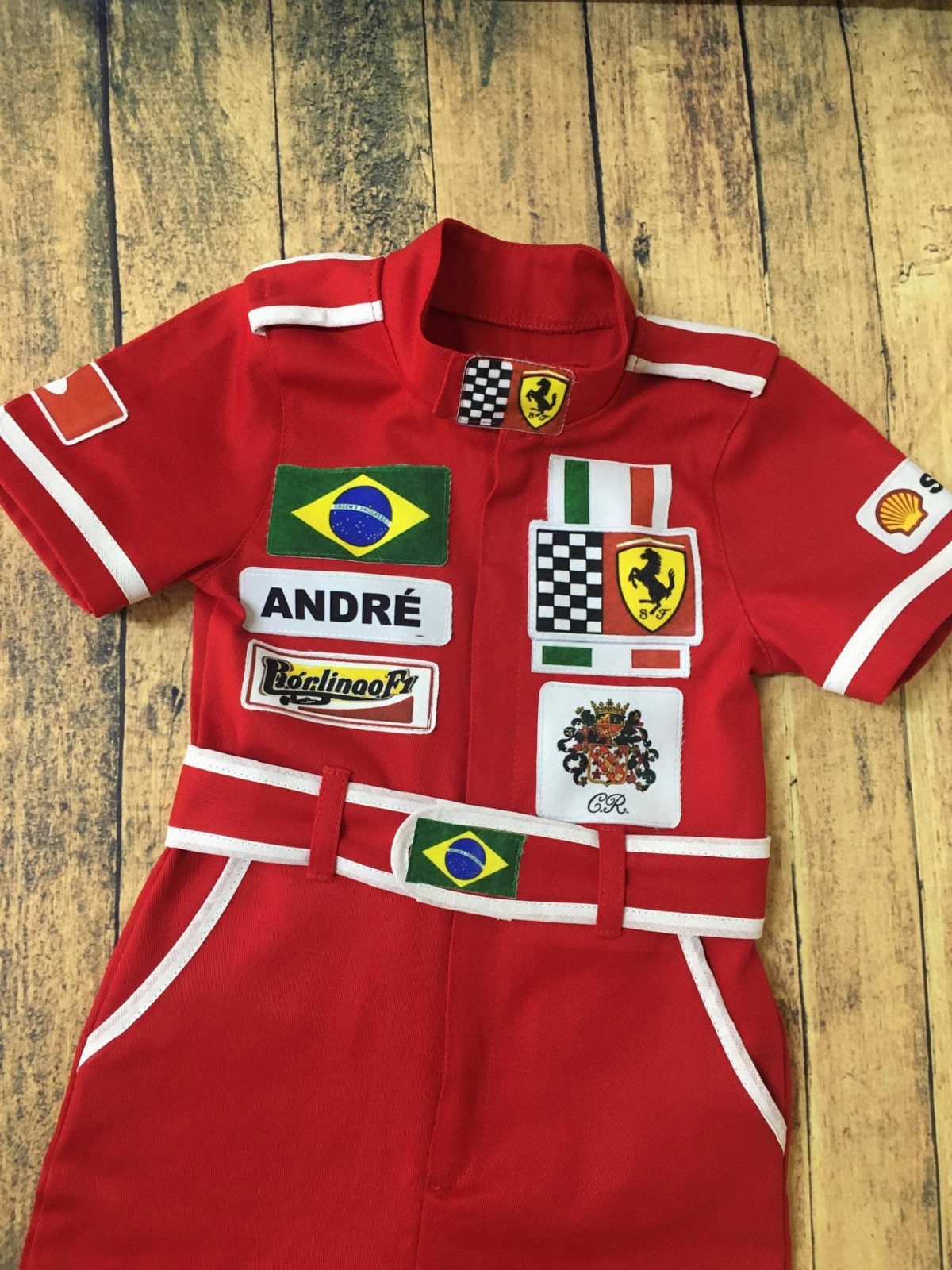 Ferrari Newborn Clothes: 8 Ideas for Red Racing Looks 2 Red infant racing jumpsuit with white trim and patches on wooden background