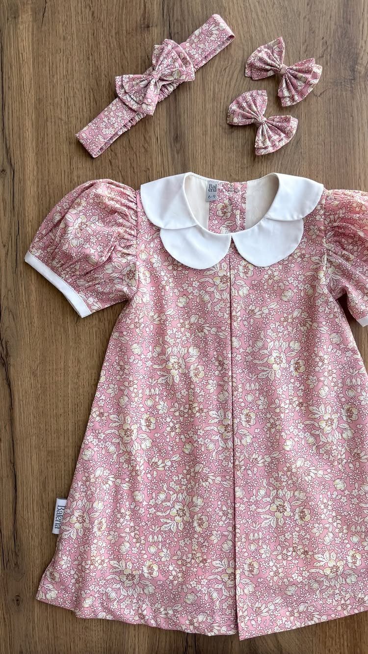 Pink floral print infant dress with white collar and matching hair accessories.