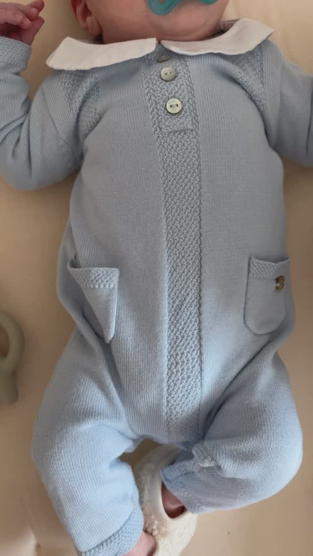 Baby wearing a light blue knitted one-piece outfit with a white collar.