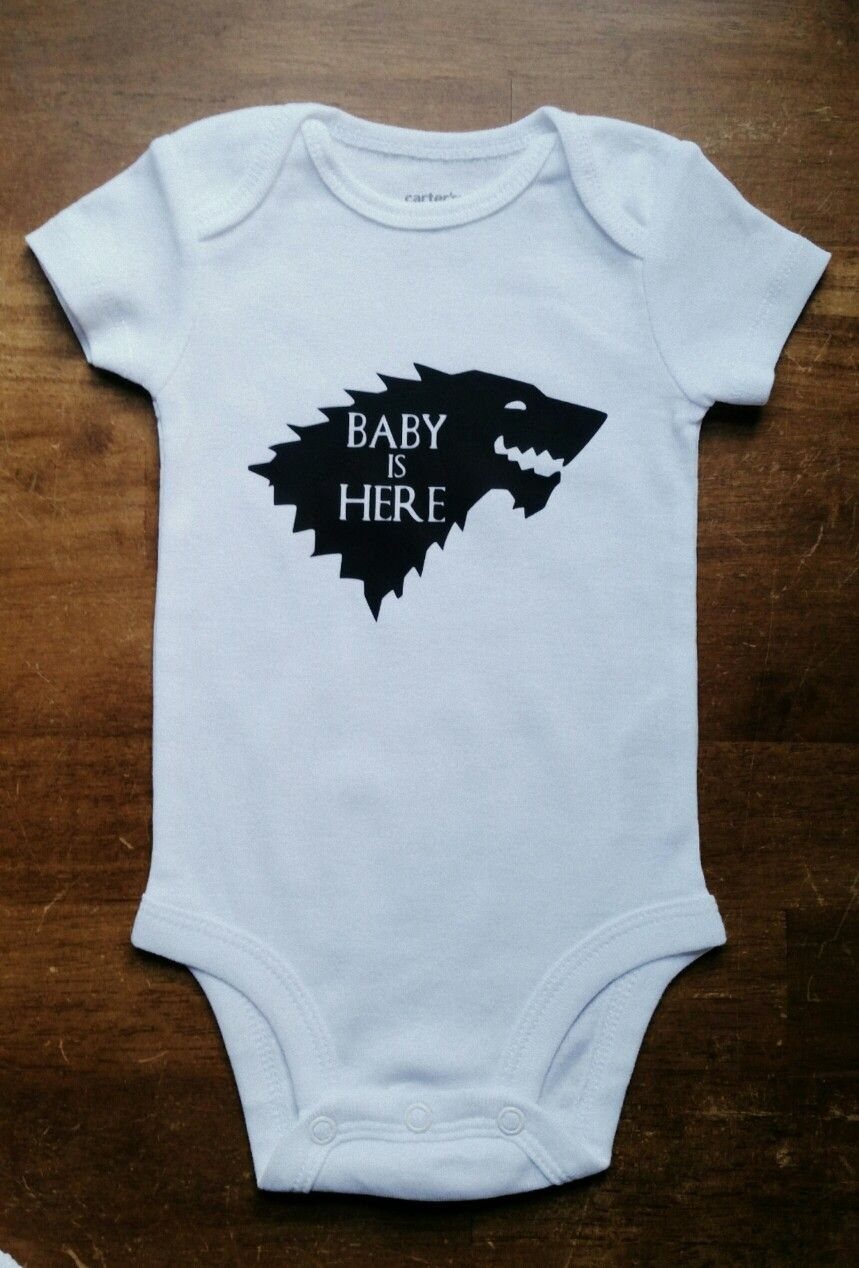 White newborn onesie with a black direwolf head and Baby Is Here text.