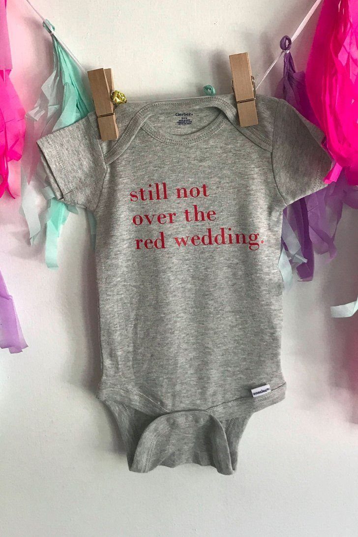 Grey newborn bodysuit with red text about the Red Wedding hanging on a line.