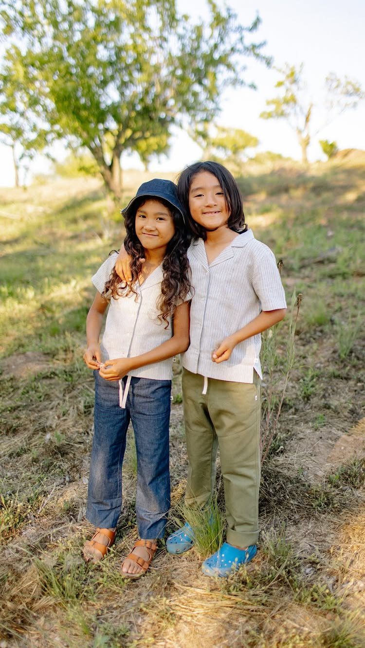 15 Gender Neutral Clothing Ideas for Everyday Style 10 Two children wearing neutral button-up shirts and trousers standing in a grassy field.