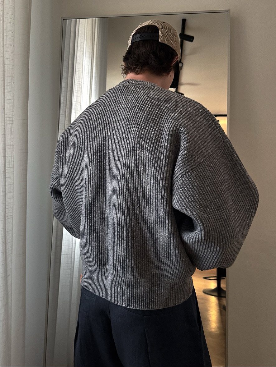 15 Gender Neutral Clothing Ideas for Everyday Style 3 Person from behind wearing a grey ribbed oversized sweater and a baseball cap.