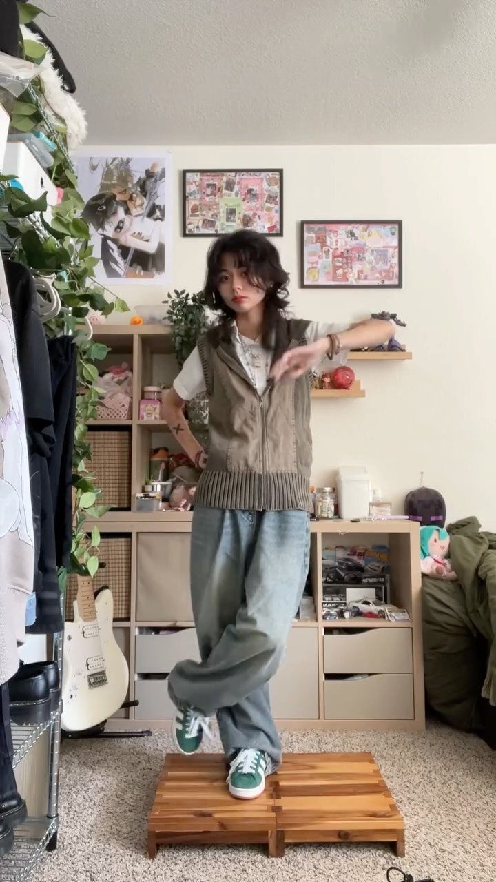 15 Gender Neutral Clothing Ideas for Everyday Style 11 Person wearing a brown utility vest and loose grey trousers standing in a room.