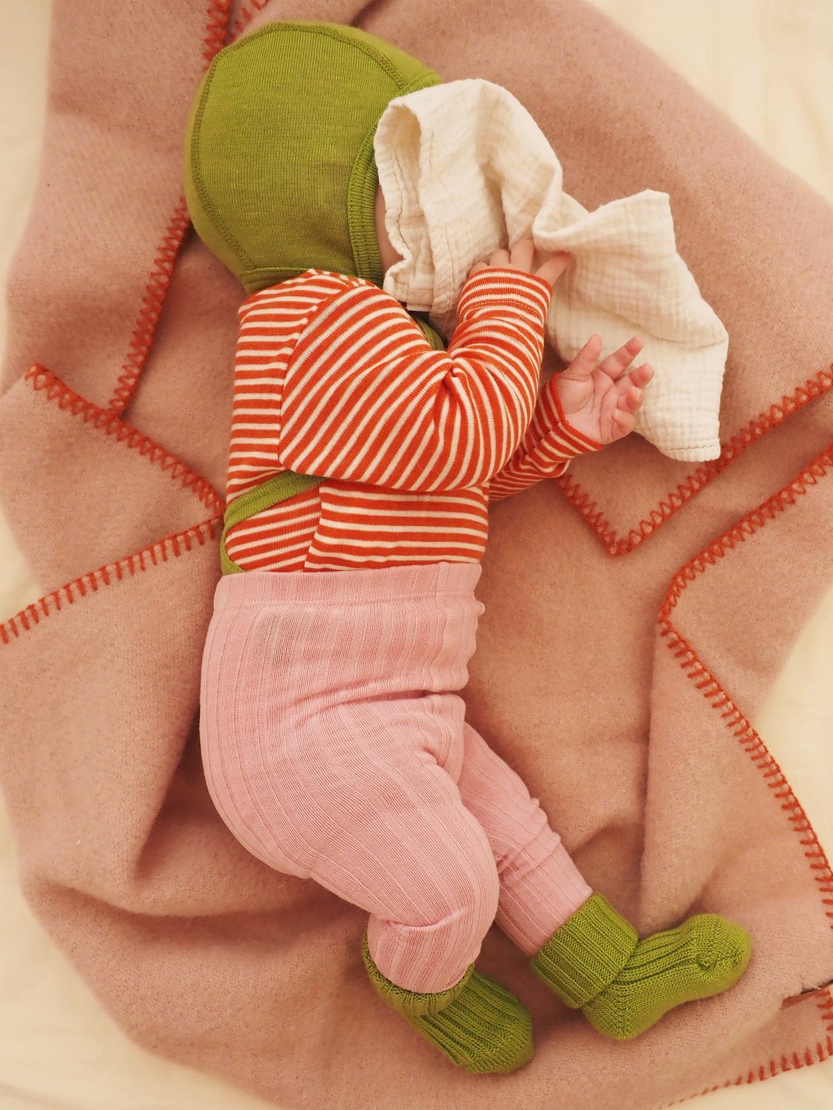 Infant St Patty's Day Clothing: 7 Ideas for Baby 5 Infant wearing a green hat, red striped shirt, and pink pants on a blanket