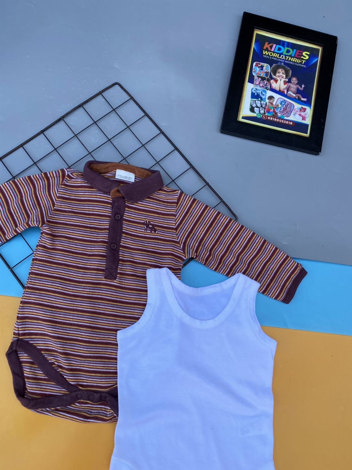 Two baby bodysuits, one striped and one white, laid on a colorful background.