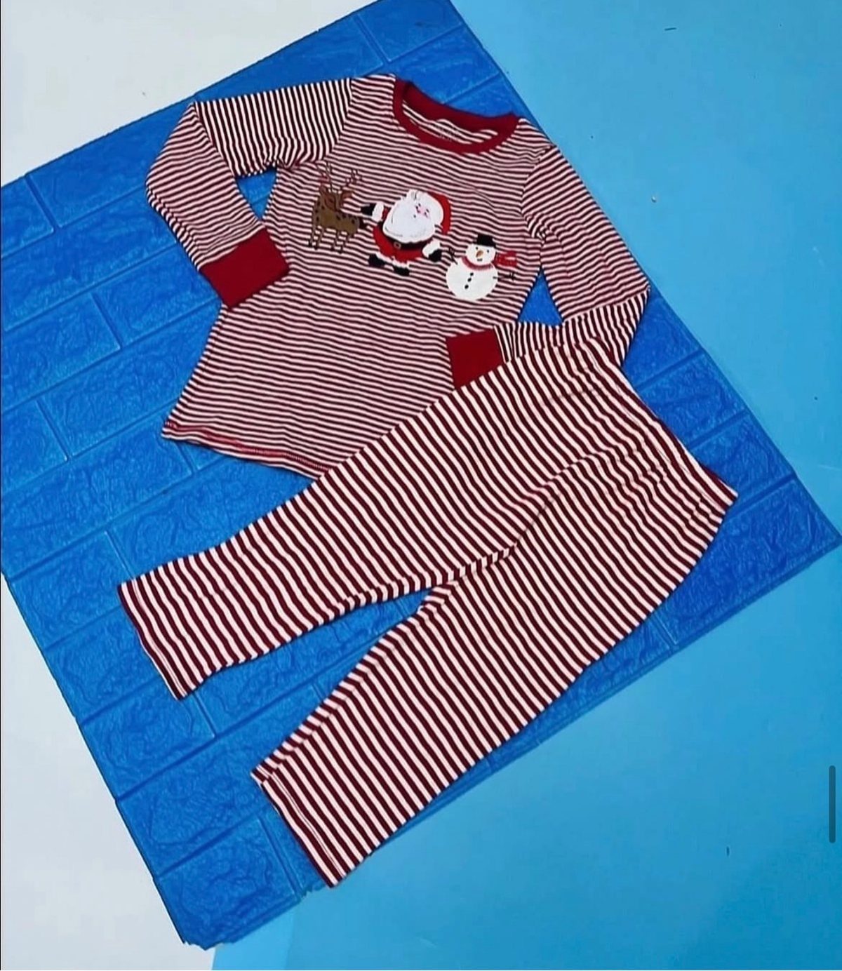 Red and white striped children's pajamas with Christmas characters on a blue background