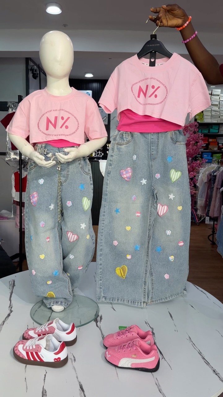 Matching pink crop tops and patched denim jeans displayed on a mannequin and hanger.