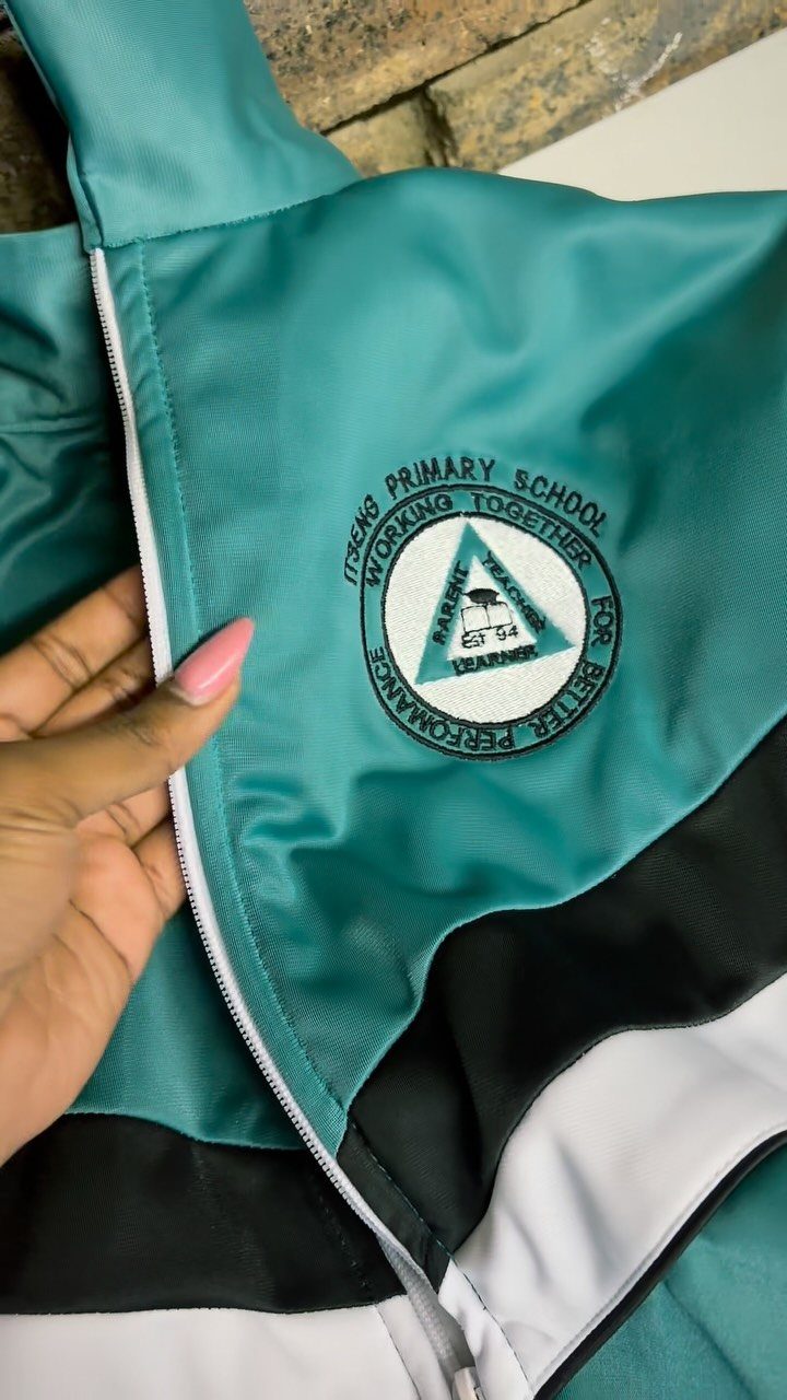 Teal school athletic jacket with a circular primary school embroidered chest patch.