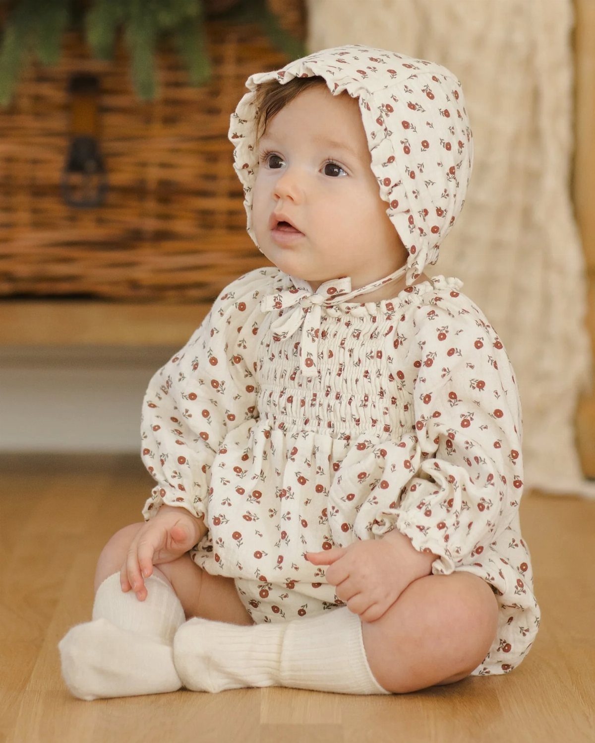 Baby wearing a cream floral print organic cotton outfit and matching bonnet.