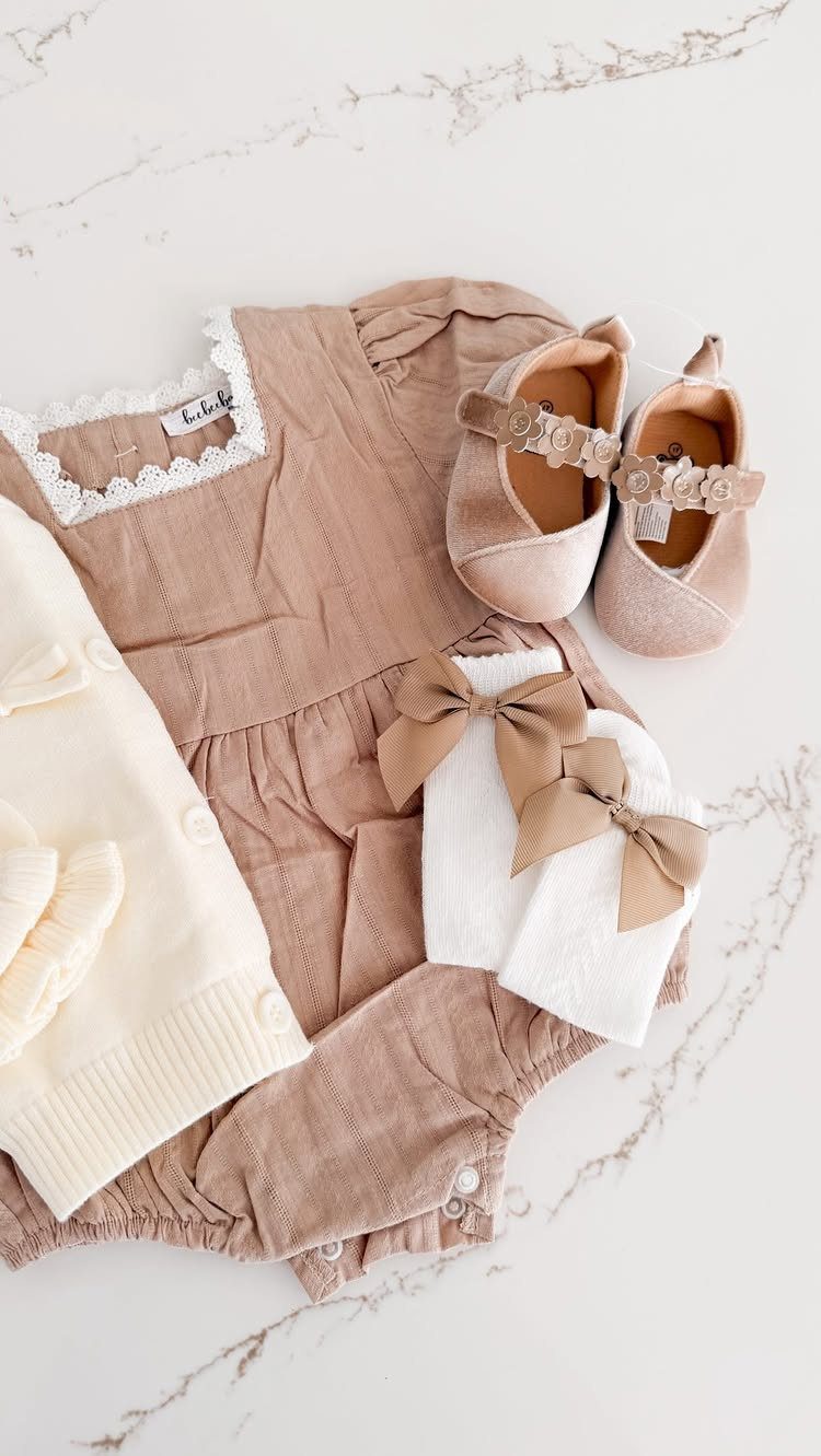 Baby outfit set with tan romper, cream sweater, shoes, and bow headbands.