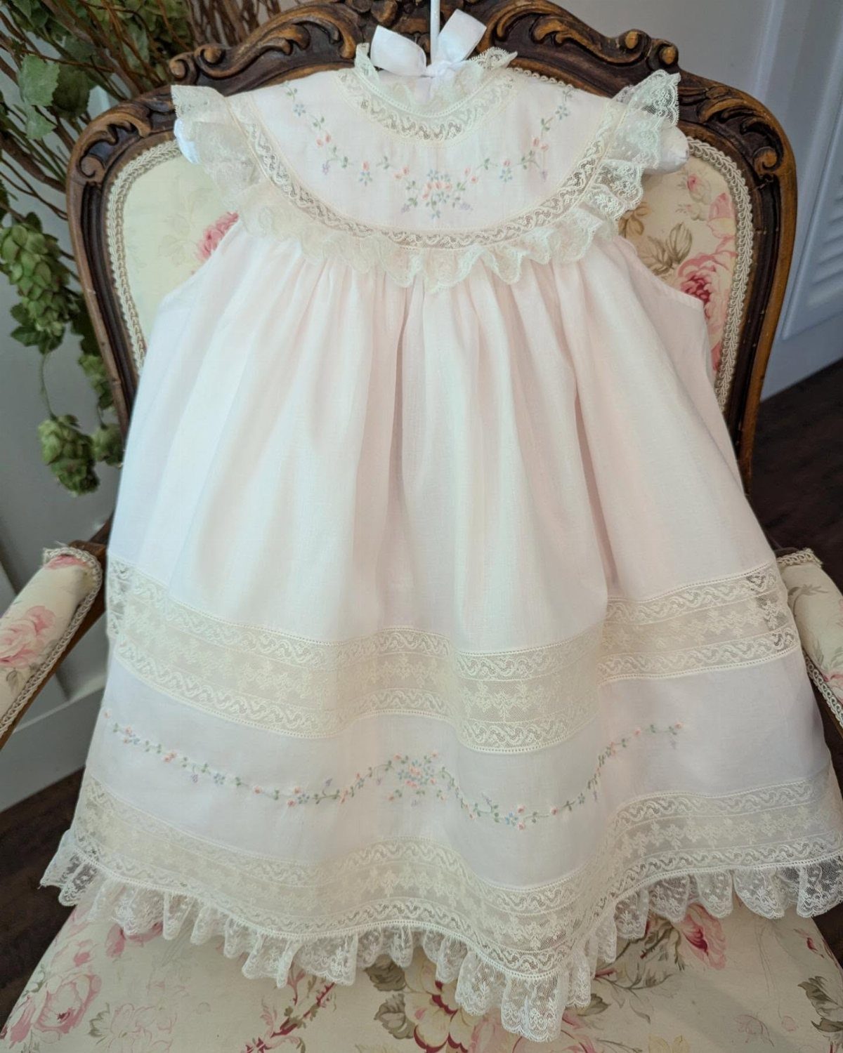 Newborn Clothes Made in USA: 3 Ideas for Gifts and Daily Wear 3 Pale pink baby dress with lace and embroidery on a vintage floral chair