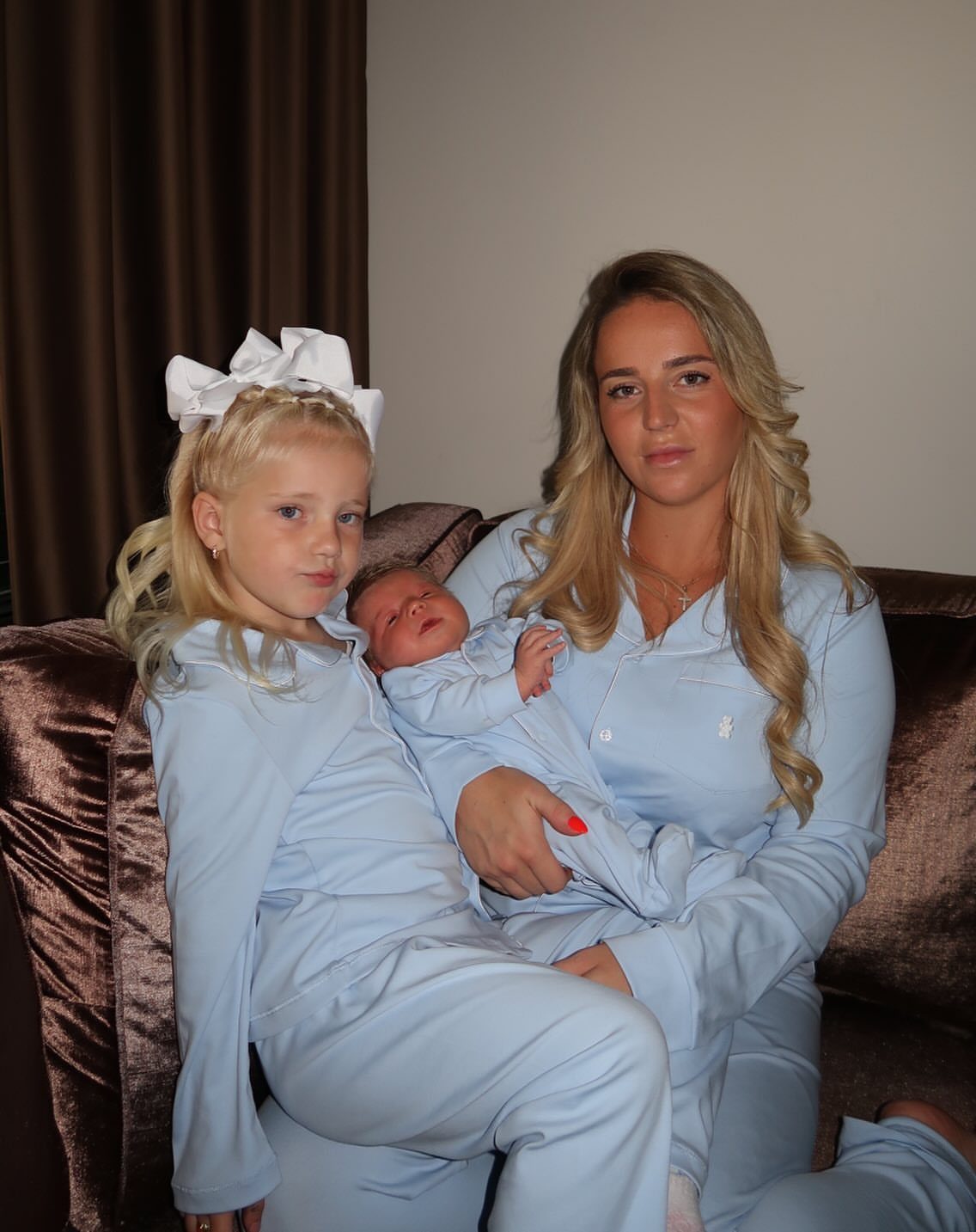 Woman, young girl, and newborn baby wearing matching light blue pajama sets.