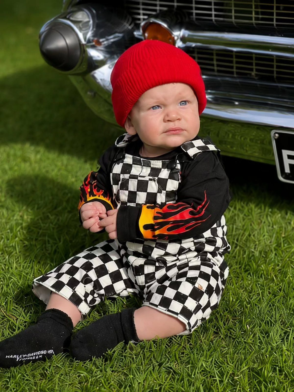 10 Rockabilly Infant Clothing Ideas for Little Rock Stars 6 Infant in checkered overalls and red beanie sitting by a vintage car.