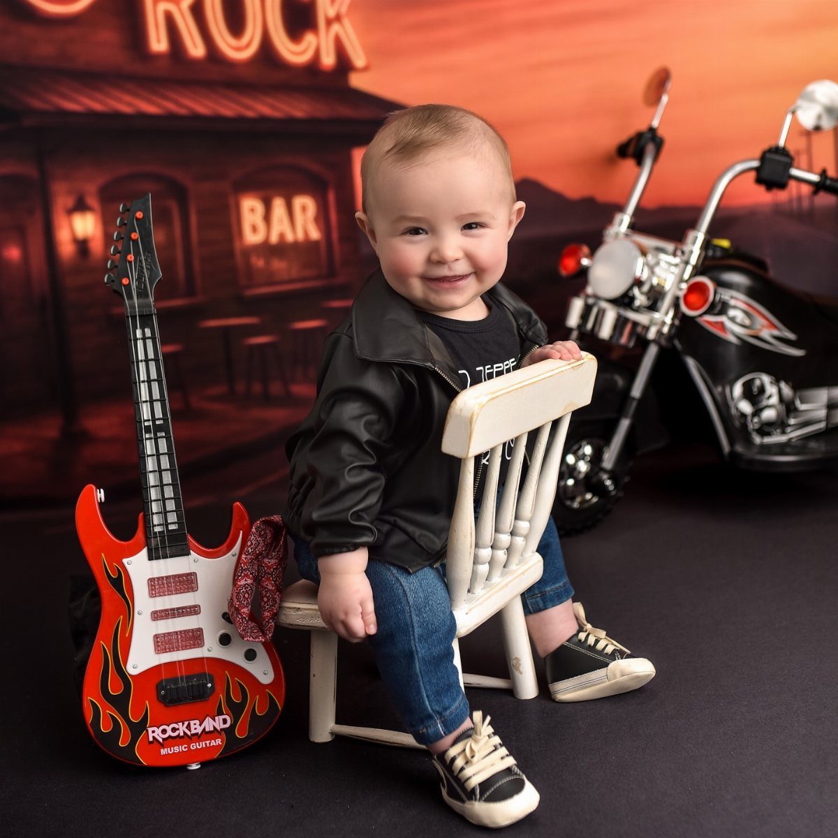 10 Rockabilly Infant Clothing Ideas for Little Rock Stars 5 Smiling infant in leather jacket and graphic tee sitting with toy guitar and motorcycle