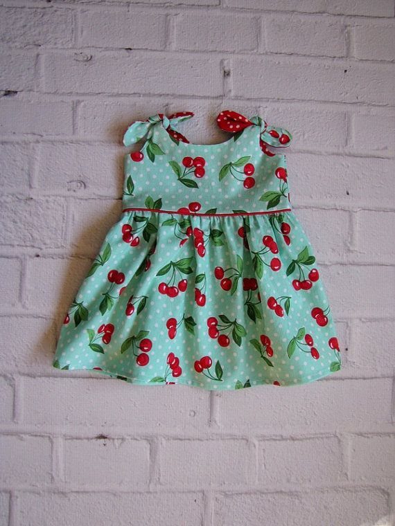 10 Rockabilly Infant Clothing Ideas for Little Rock Stars 7 Light blue infant dress with cherry prints and polka dots on white brick wall