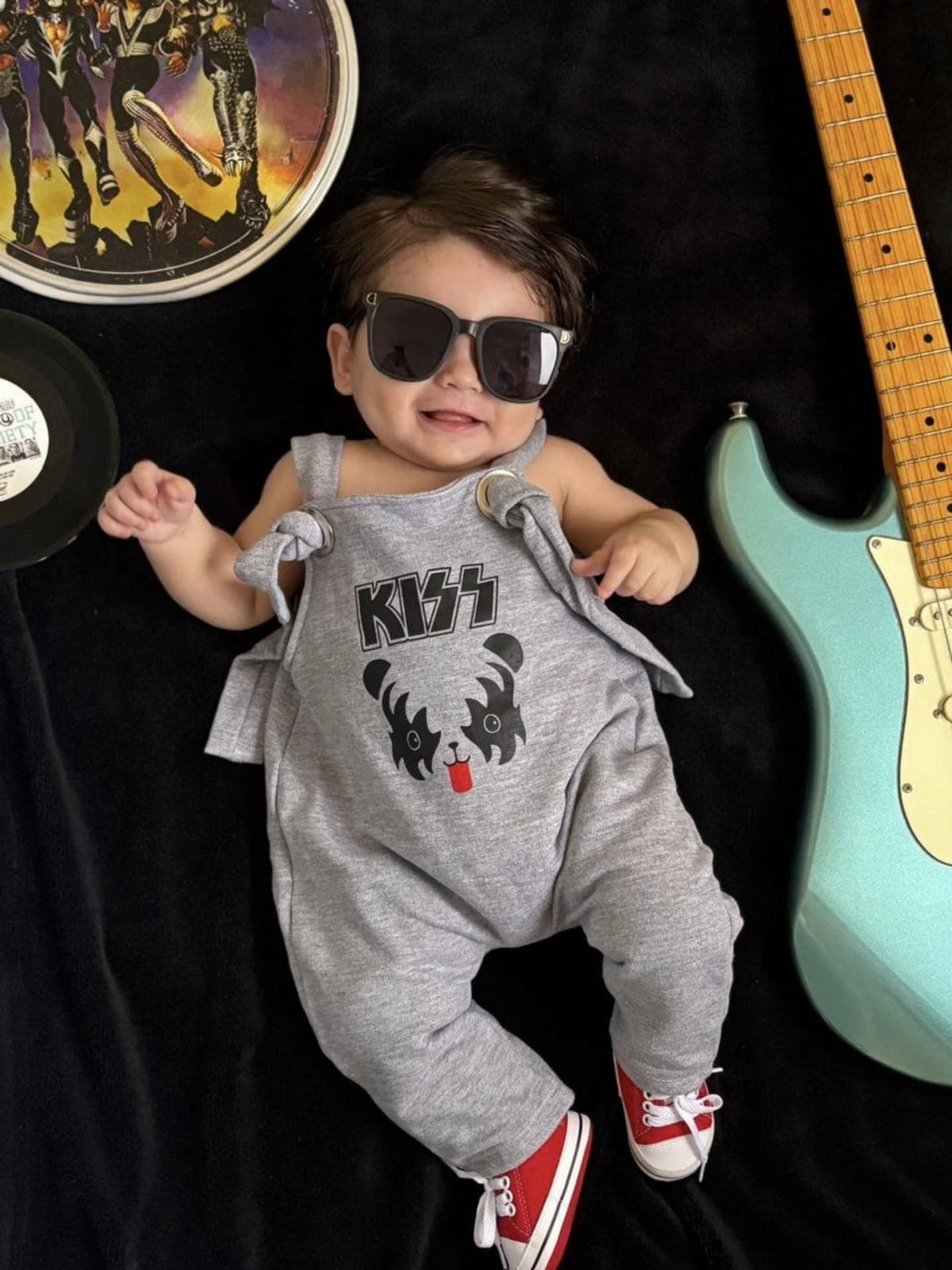 10 Rockabilly Infant Clothing Ideas for Little Rock Stars 10 Baby in grey KISS band romper and sunglasses lying next to electric guitar